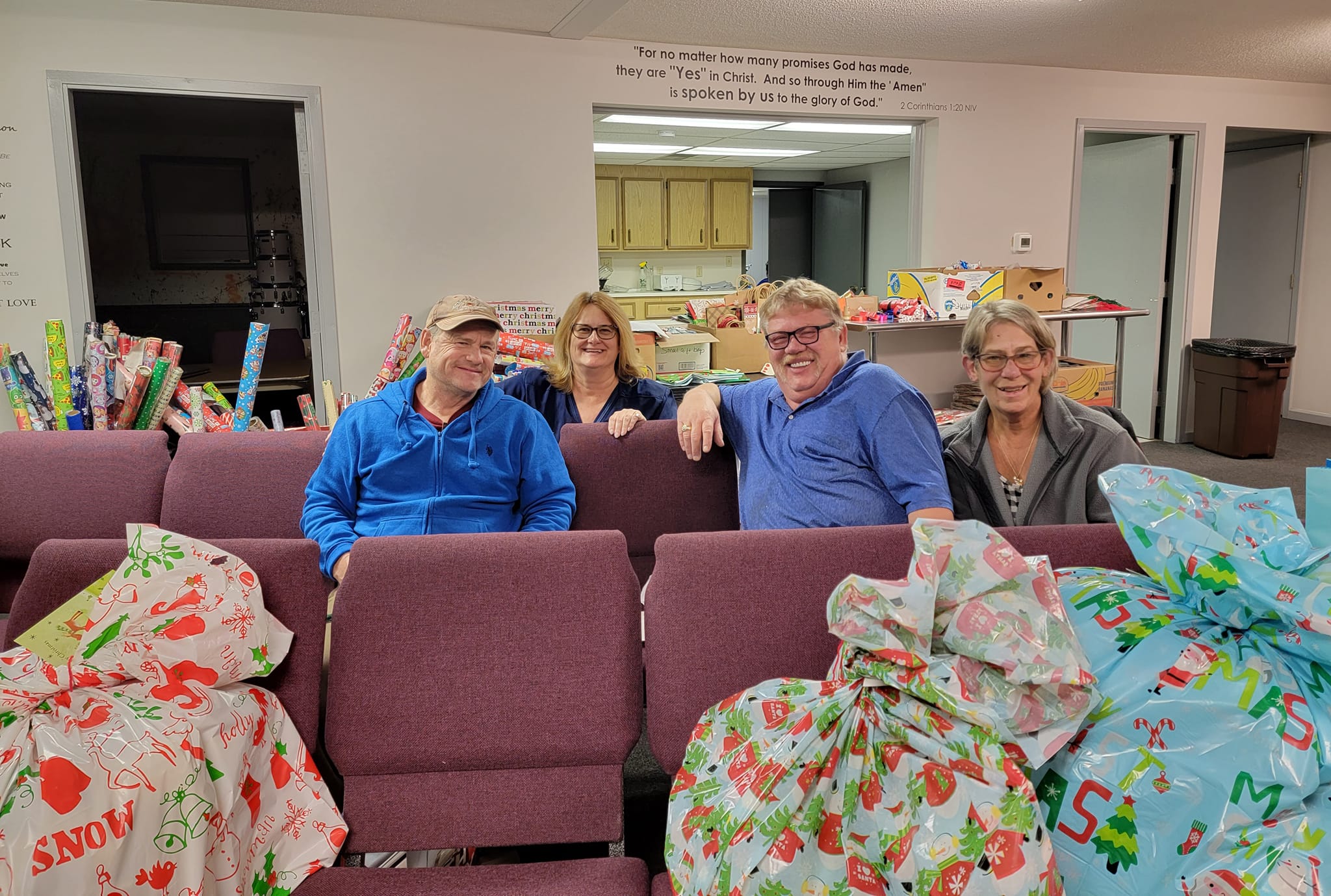 Volunteers seated together surrounded by wrapped gifts