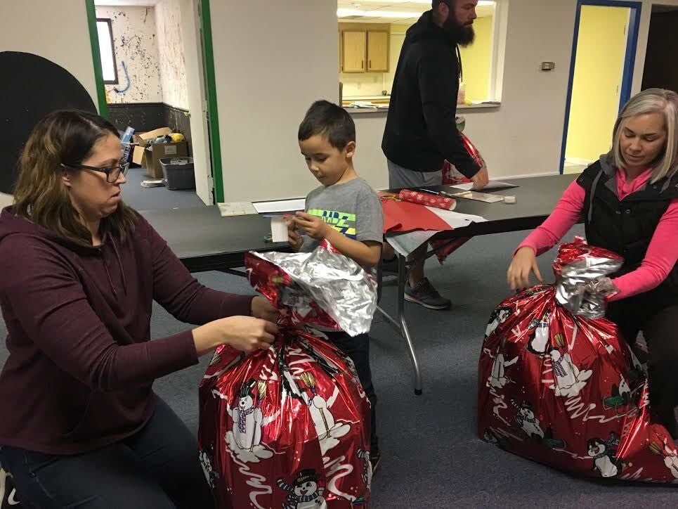 Volunteers and a child packing gifts into red bags